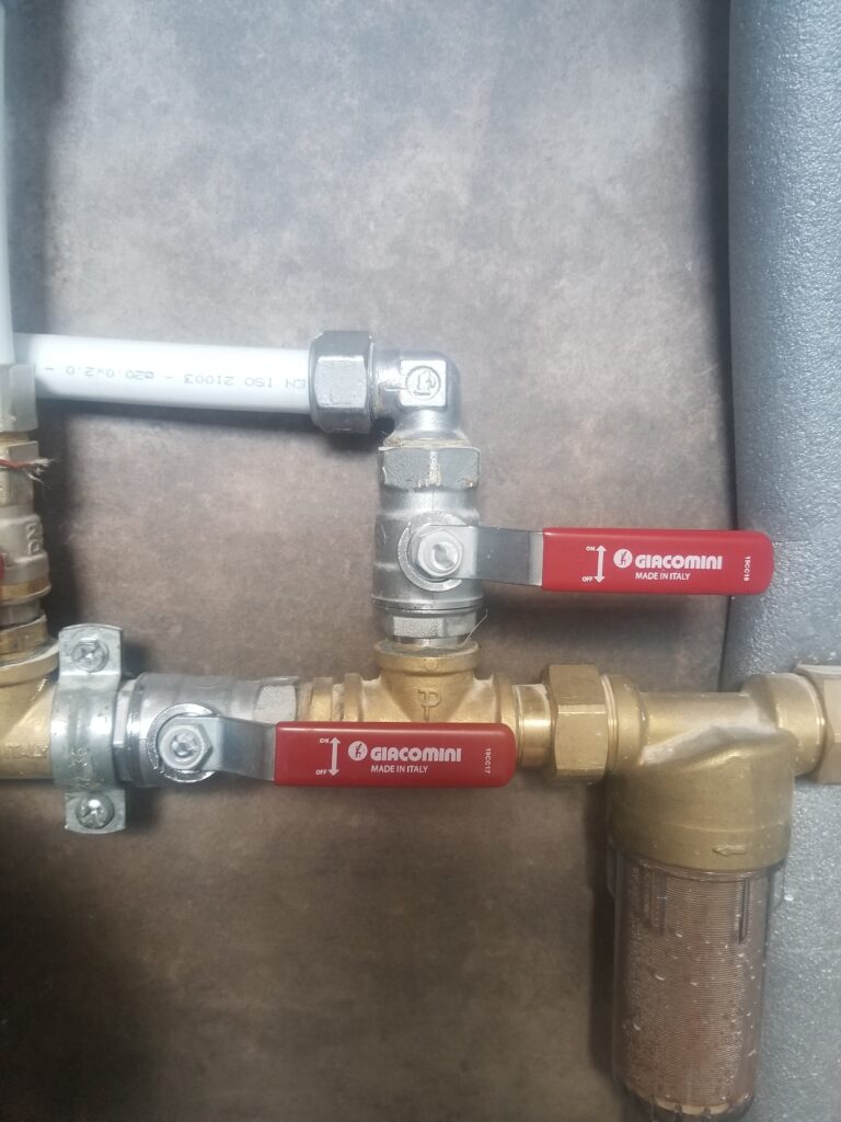 Two lever-operated ball valves on different pipe branches, one handle across its pipe and one aligned with its pipe.