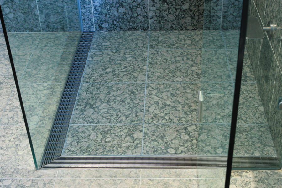 Linear shower drain grating along the edge of a tiled shower