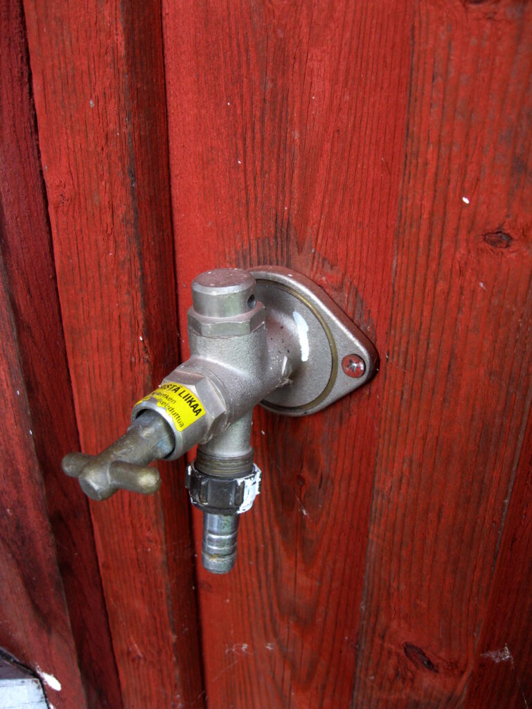 Outdoor faucet leaking inspection points: projecting handle stem, downward outlet, hose connection, and wall flange.