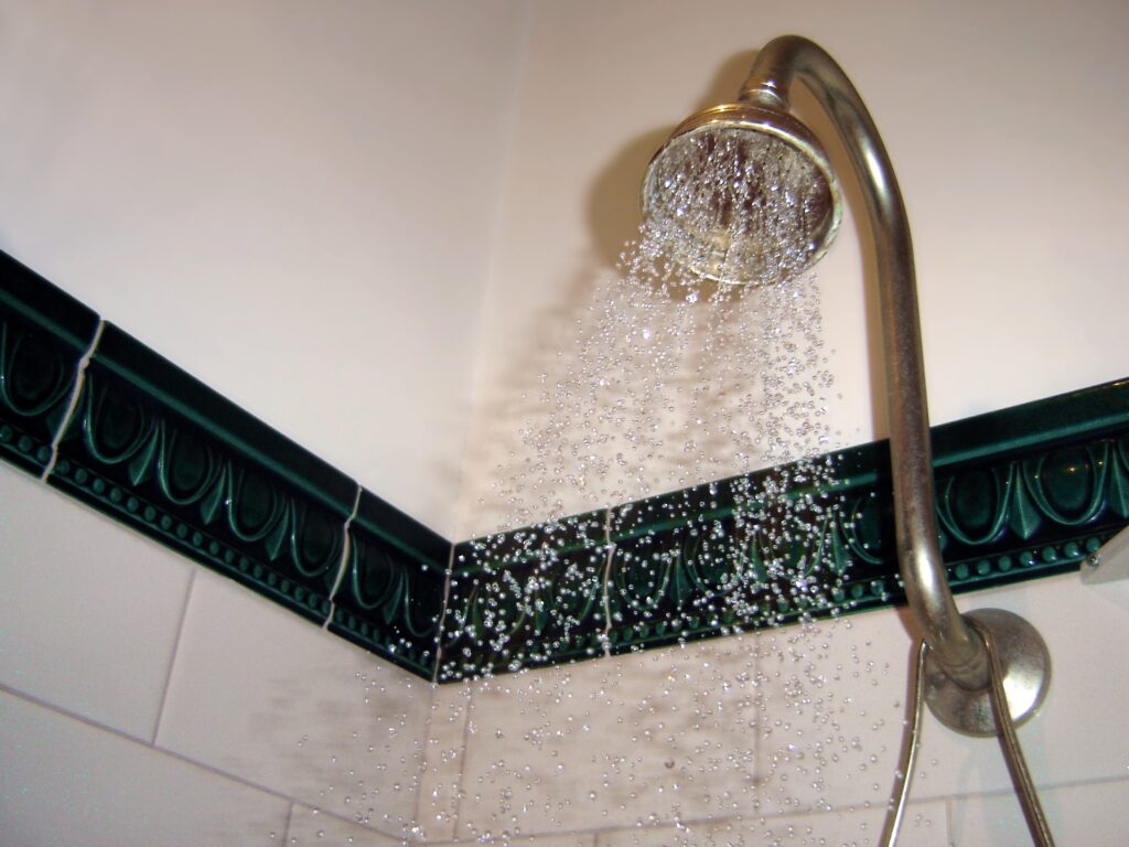 Operating shower with water leaving the spray face and the arm connection visible above it.