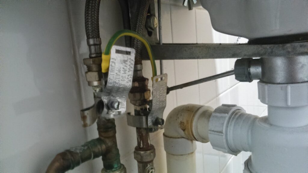 Under-sink inspection locations: braided supply hoses and metal connections at left, and white plastic drain joints at right.