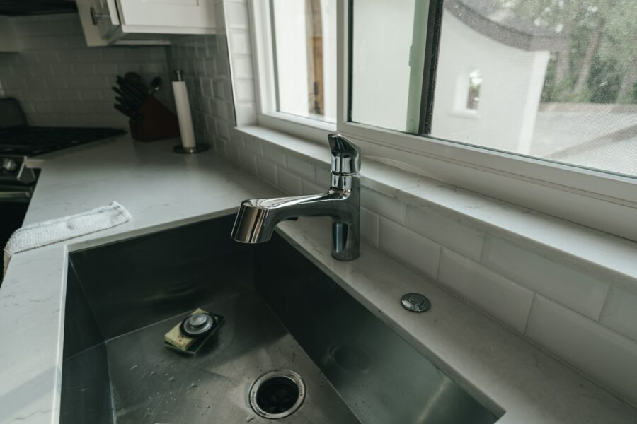 Chrome single-lever faucet above a stainless-steel kitchen sink beside a window.